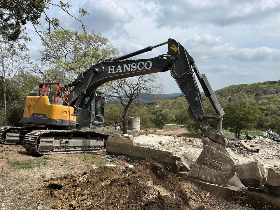 Hansco excavator lifting broken concrete slabs out of a residential lot