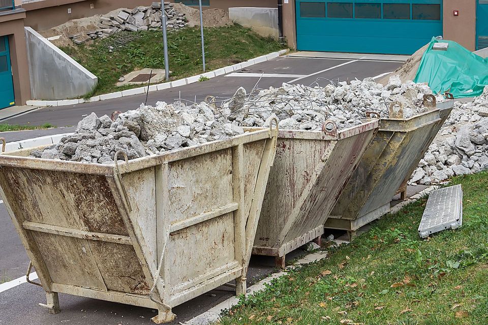 Roll-off bins filled with crushed concrete sorted for recycling at a demolition site
