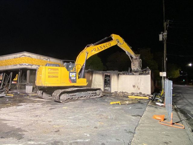 Hansco excavator demolishing a commercial building at night under work lights