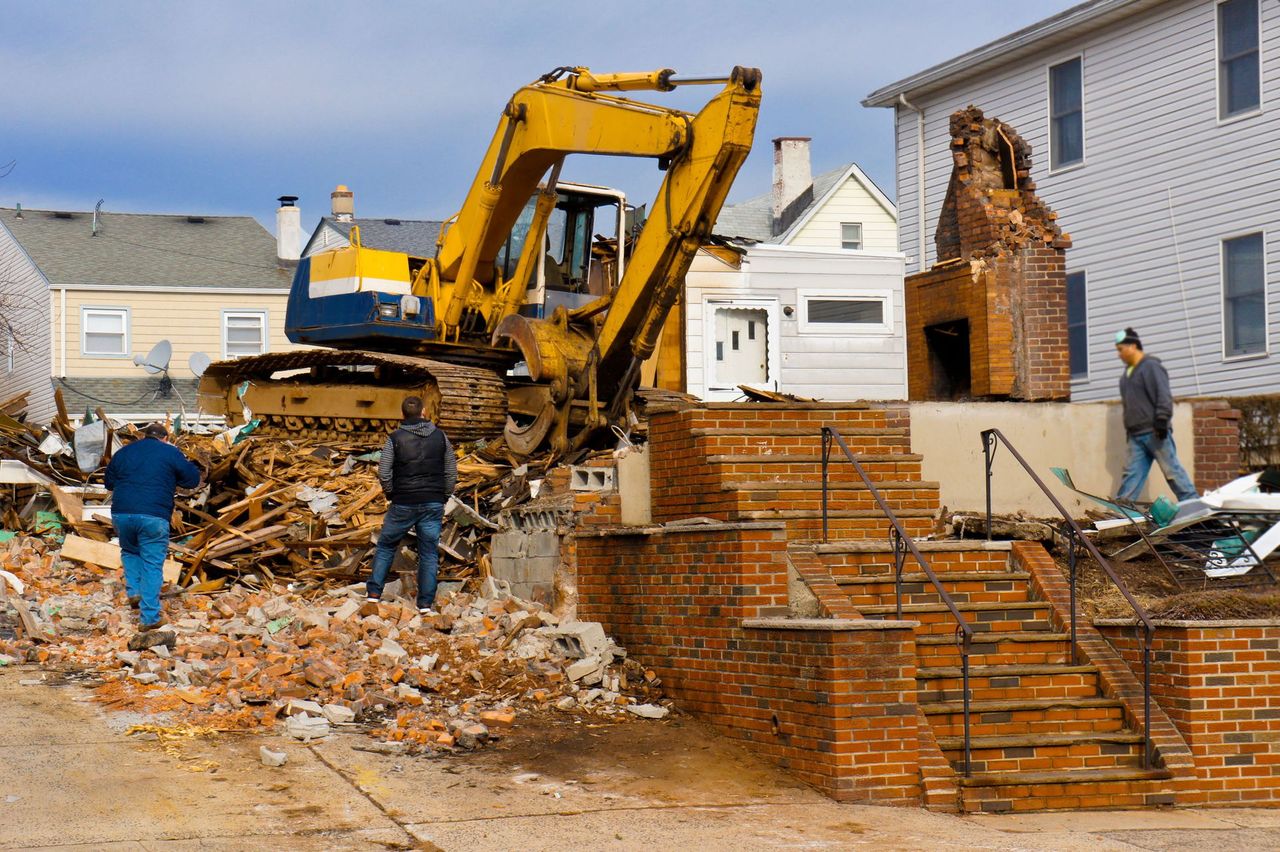 Demolition crew working beside an excavator on a residential job